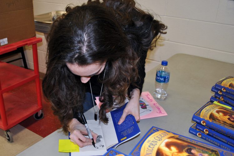 Author Kamilla Benko signs copies of books purchased by students.
